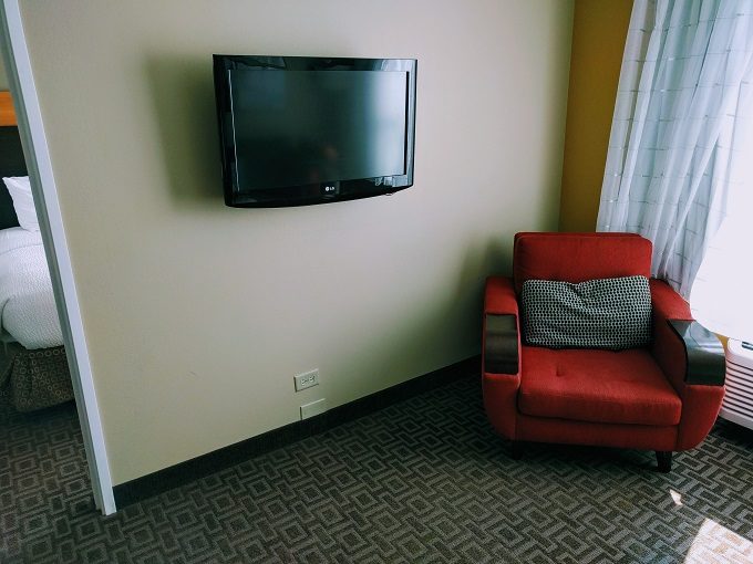 TownePlace Suites Chicago Naperville, Illinois - TV & armchair in living room